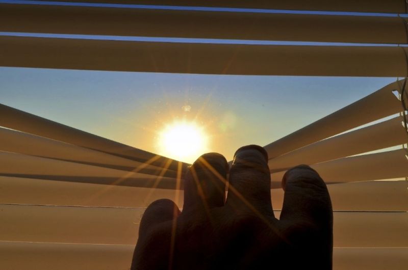 Door de jaloezieën kijkend naar een zomerse zon