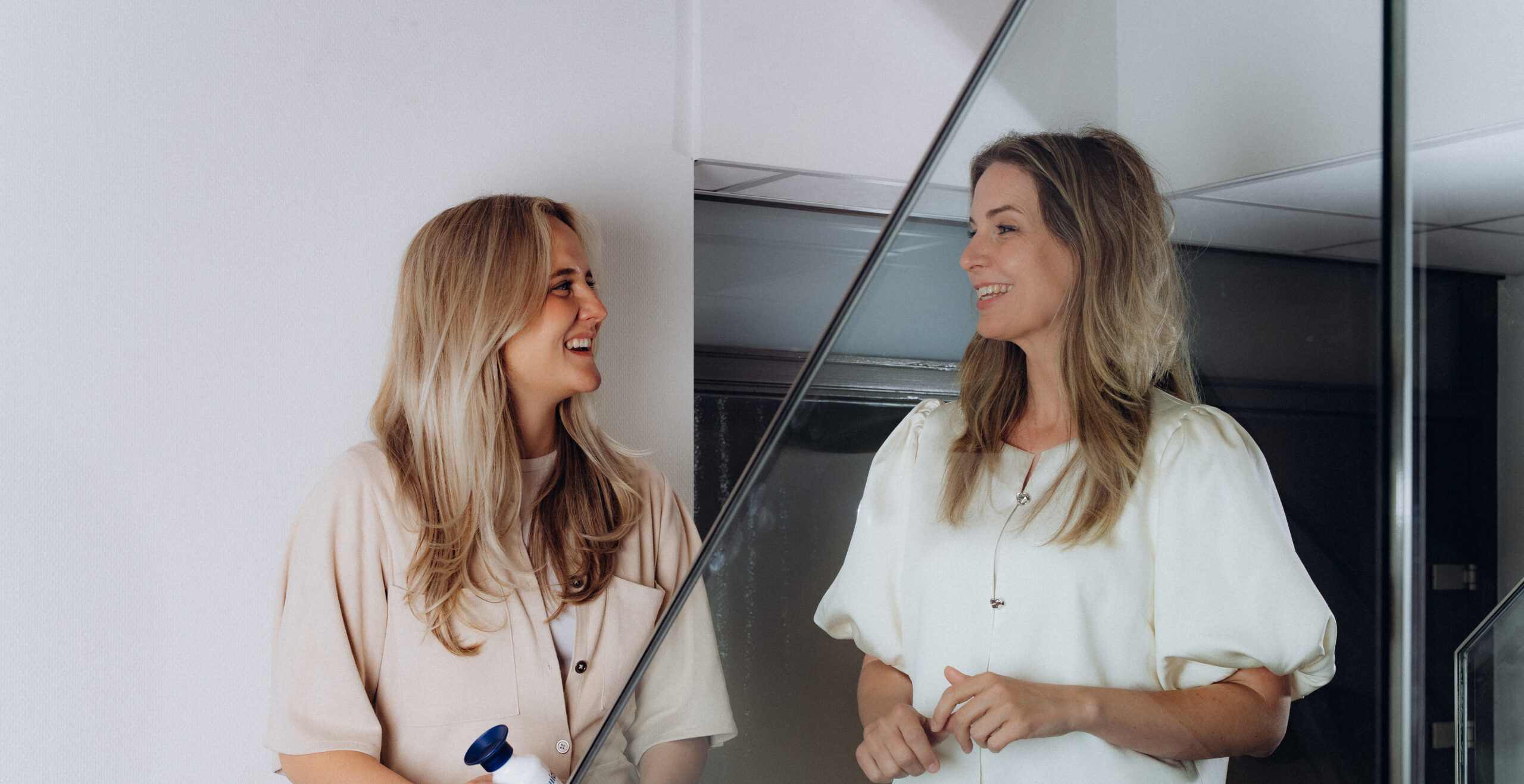 Twee lachende vrouwelijke collega's die staan te praten op de trap