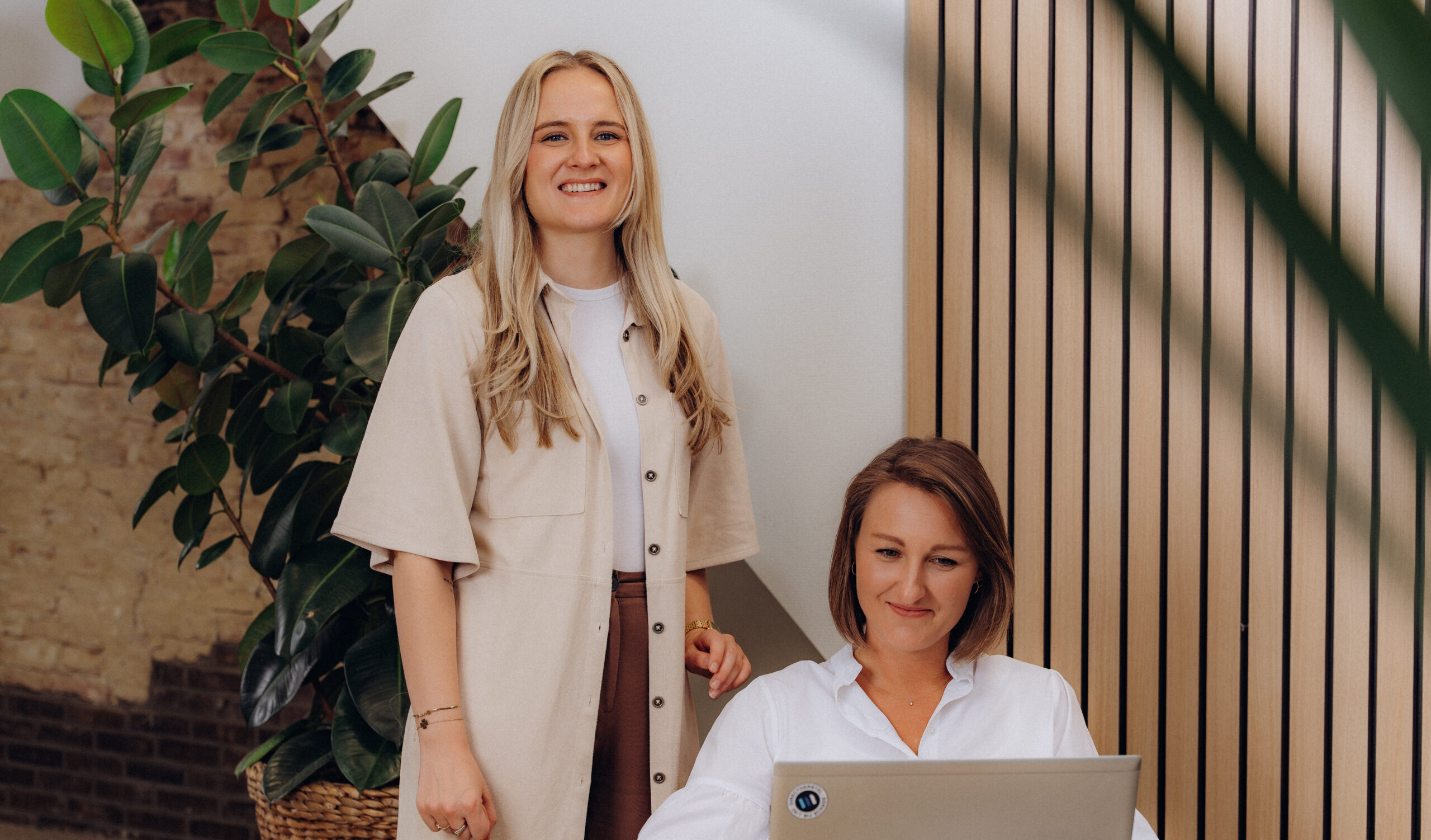 Twee vrouwelijke Midglas collega's lachend en kijkend naar de camera