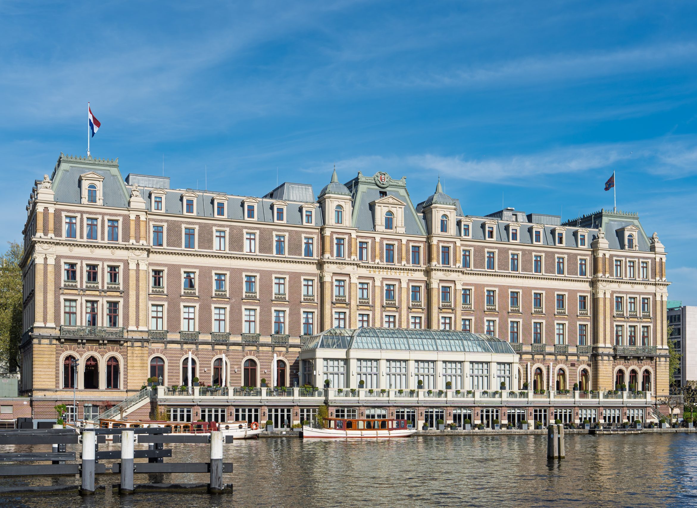 Een schilderachtig uitzicht op een groots historisch luxe hotelgebouw gelegen aan de Amstel in Amsterdam. De elegante architectuur is vastgelegd op een heldere zonnige dag.
